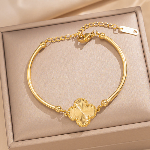 A gold bangle bracelet with a four-leaf clover charm.